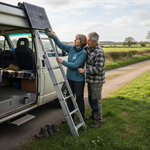 Couple setting up solar panels on campervan in UK meadow