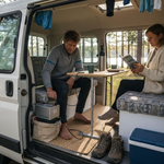 Couple using campervan energy system at lakeside camp