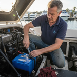 Boat owner installing lithium battery aboard cabin cruiser