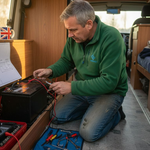 Man inspecting lithium battery setup in campervan