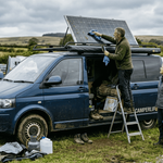 Couple cleaning solar panel on campervan