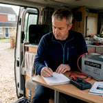 Man checks energy storage setup in campervan