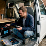 Man checking campervan lithium battery inside van