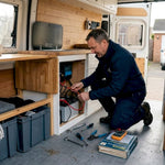 Man wiring batteries in campervan interior