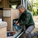 Technician installing lithium battery in campervan