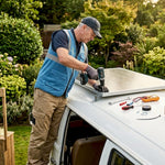Man installs solar panel on campervan roof